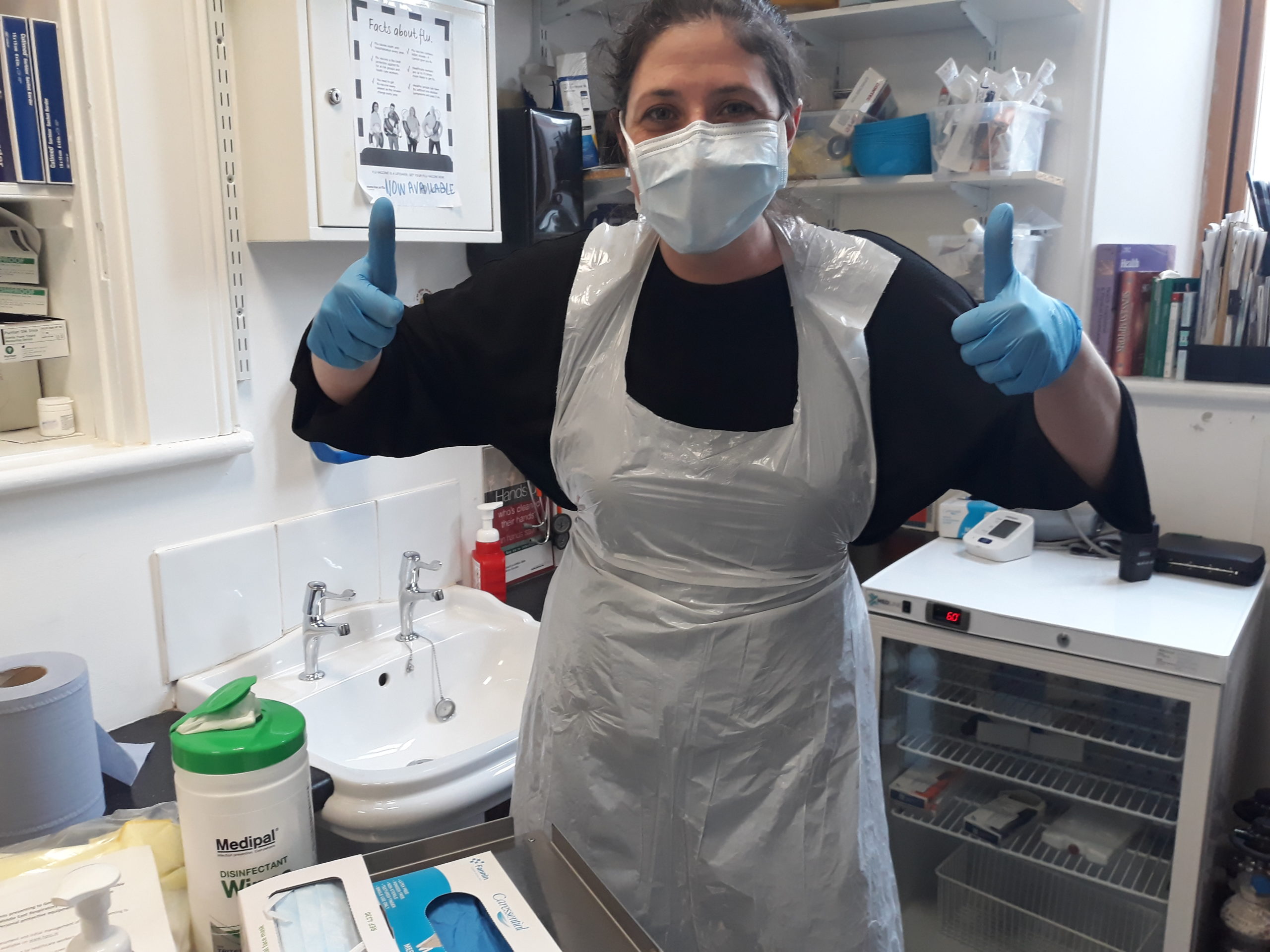 Nurse at Depaul's nurses station in a Depaul Homeless Service in full PPE gear giving a thumbs up