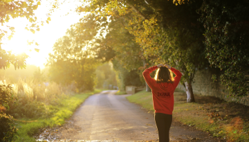 Woman in a Depaul hoody walking down a country lane in the sunset