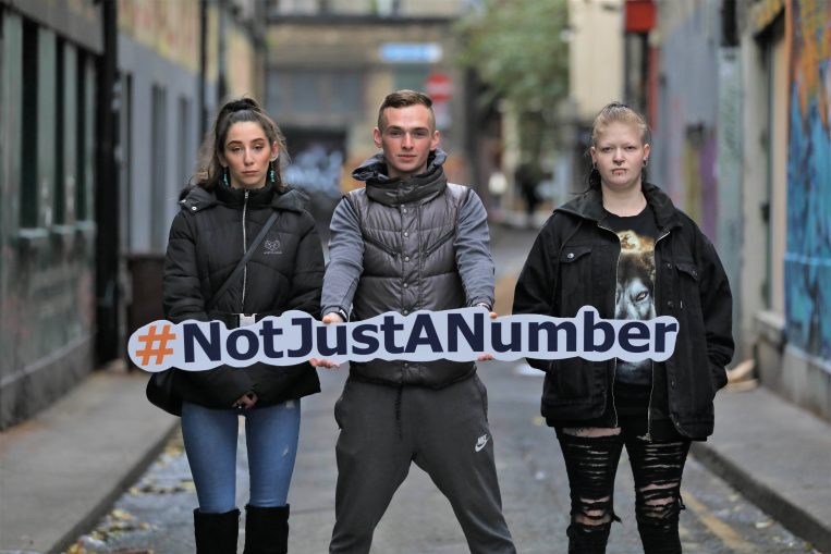 3 service users from Depaul's Peter's Place pose with a sign that says #NotJustANumber